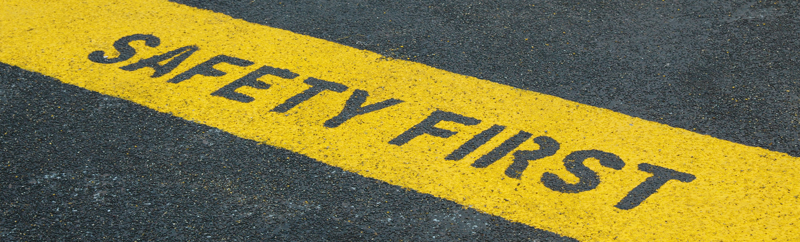 Pavement with yellow strip with “safety first” outlined