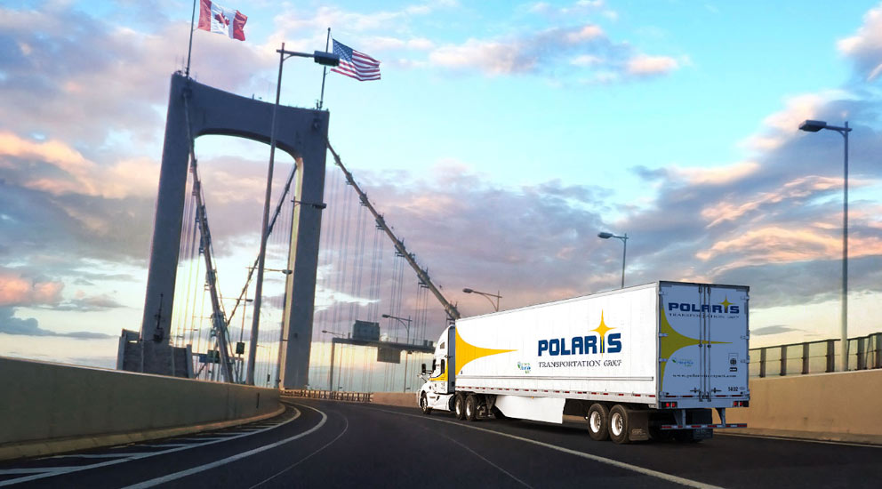 Polaris transport truck and trailer crossing a bridge with a Canadian and American flag on top, at the border