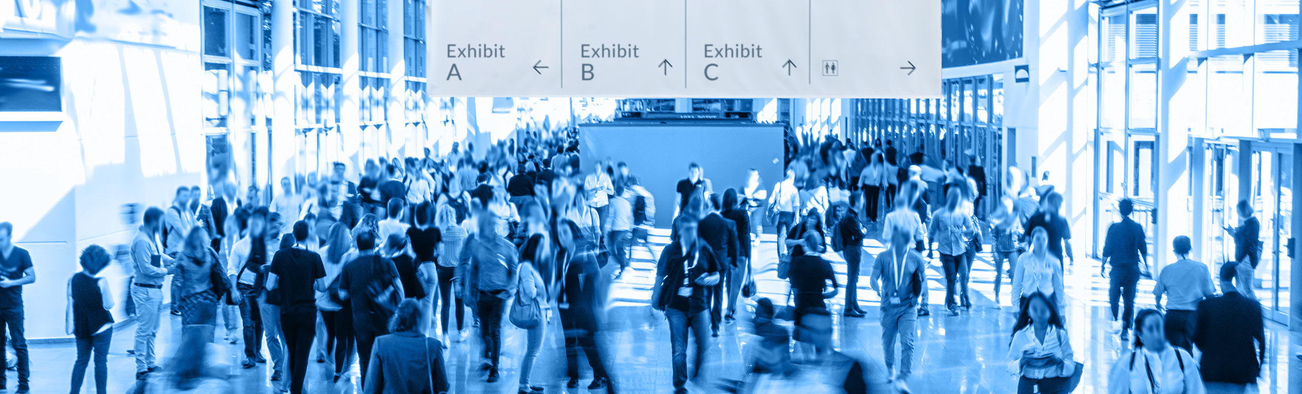 A trade show exhibition hall with lots of people and signage showing direction of different exhibits
